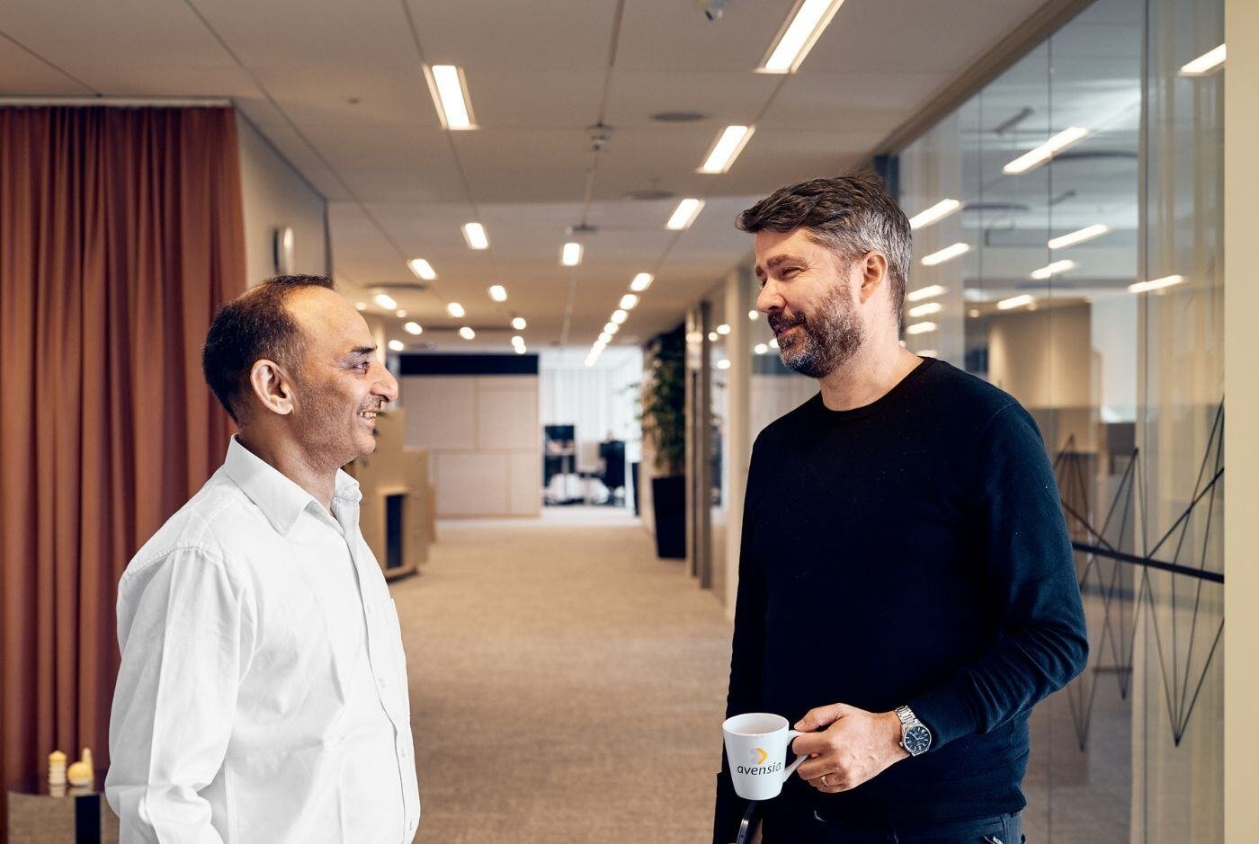 Två manliga kollegor som står och pratar på kontoret